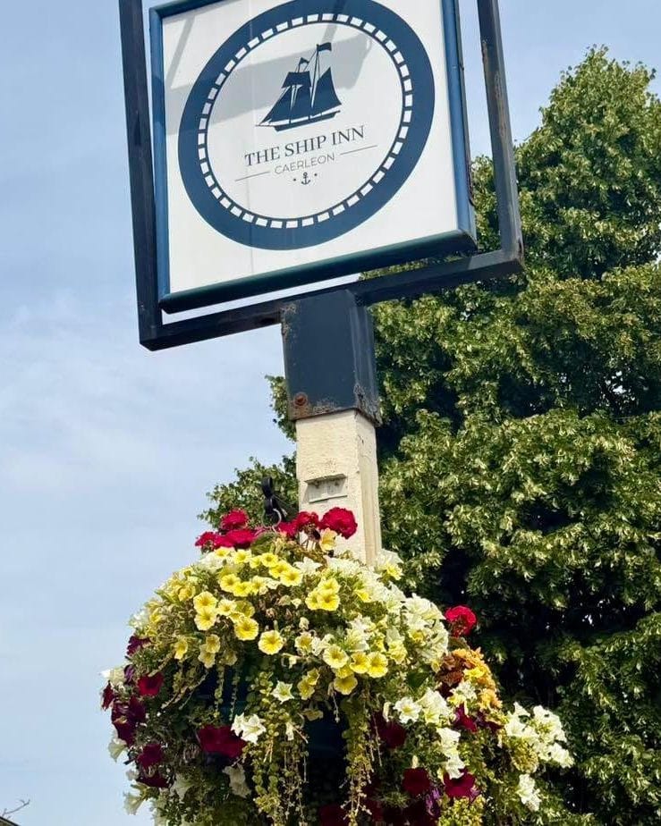 The hanging sign for The Ship Inn Caerleon above a basket of summer flowers